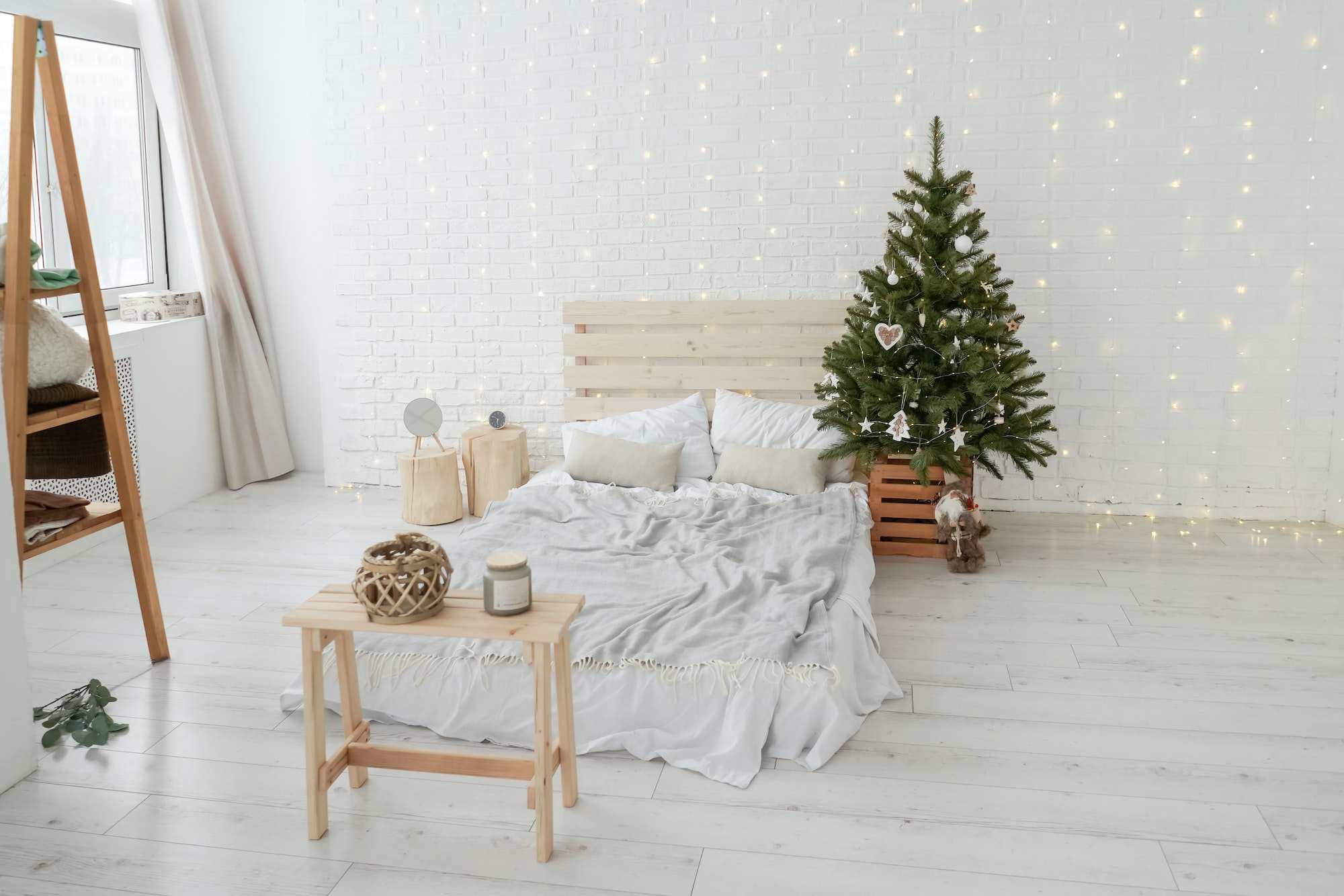 Christmas tree in bed room. Light interior.