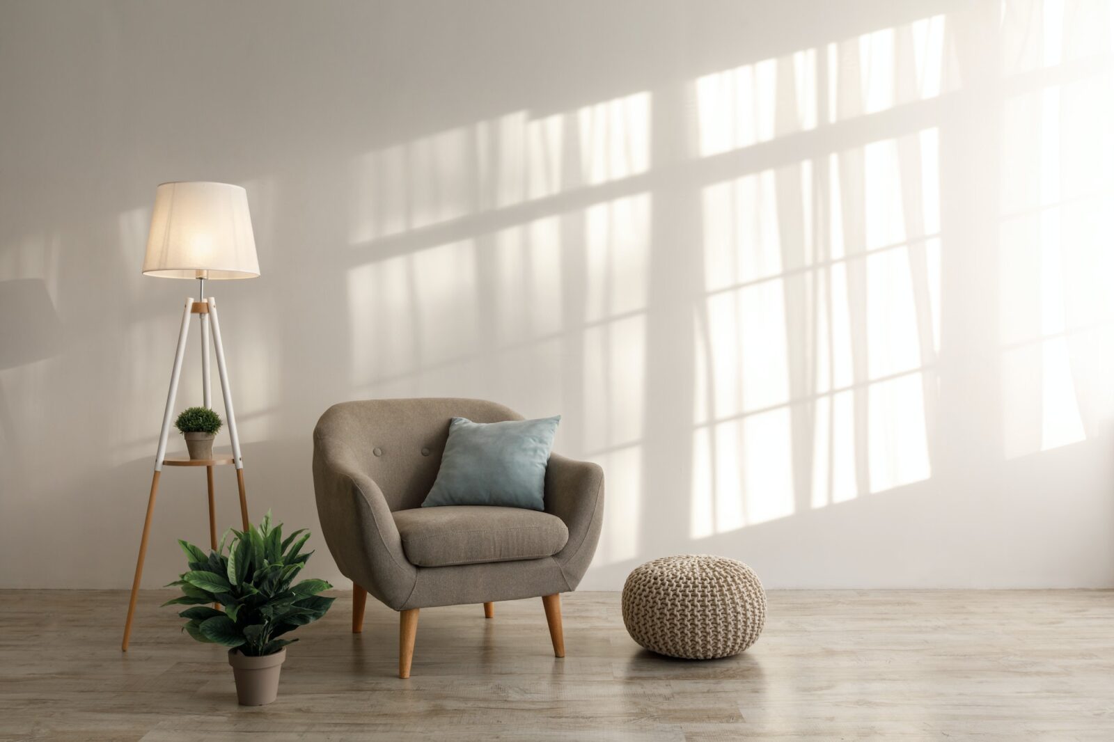 Comfortable retro armchair with pillow, luminous lamp and plant in pot, ottoman on floor