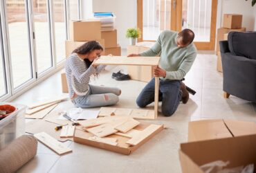 Couple In New Home On Moving Day Putting Together Self Assembly Furniture