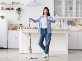Happy woman showing thumbs up cleaning floor with spray mop