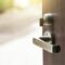 Open the modern wooden door with metal door handles lock to see outside nature view (Outdoors).