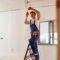Smiling electrician fixing electric cable on ceiling