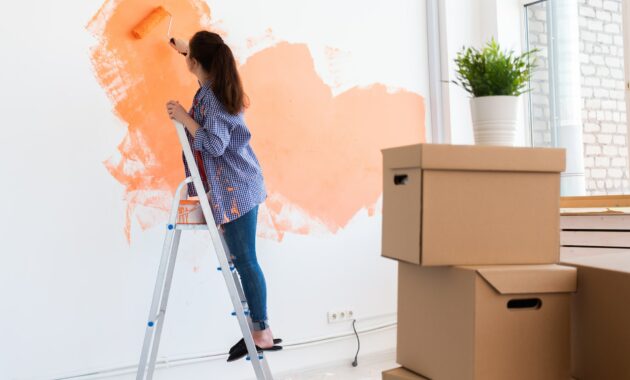 Cheerful woman painting the walls of new home. Renovation, repair and redecoration concept