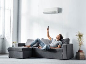 handsome man lying on sofa and switching on air conditioner