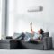 handsome man lying on sofa and switching on air conditioner