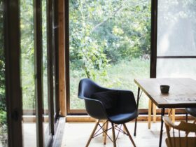 Interior view of residential building with black chair and wooden table, glass walls.