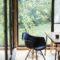 Interior view of residential building with black chair and wooden table, glass walls.