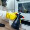 pest control worker standing with sprayer in kitchen
