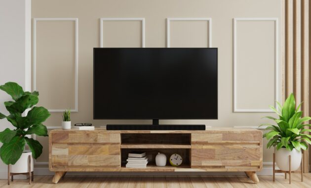 TV on cabinet with cream color wall and wood flooring