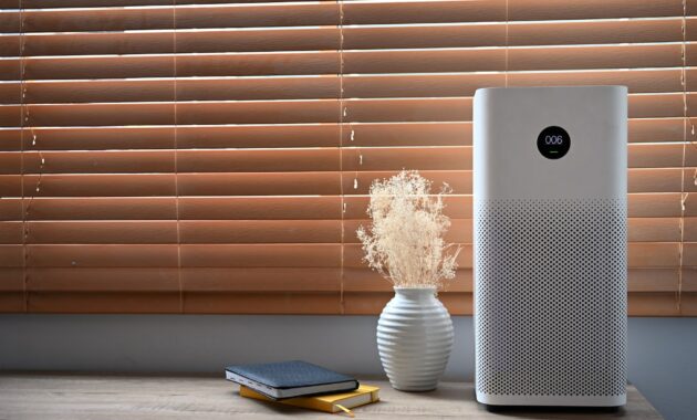 Air purifier in front of windows in living room for fresh air and healthy life.