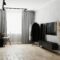Modern living room interior with gray walls, clothes rack and floor mirror, TV