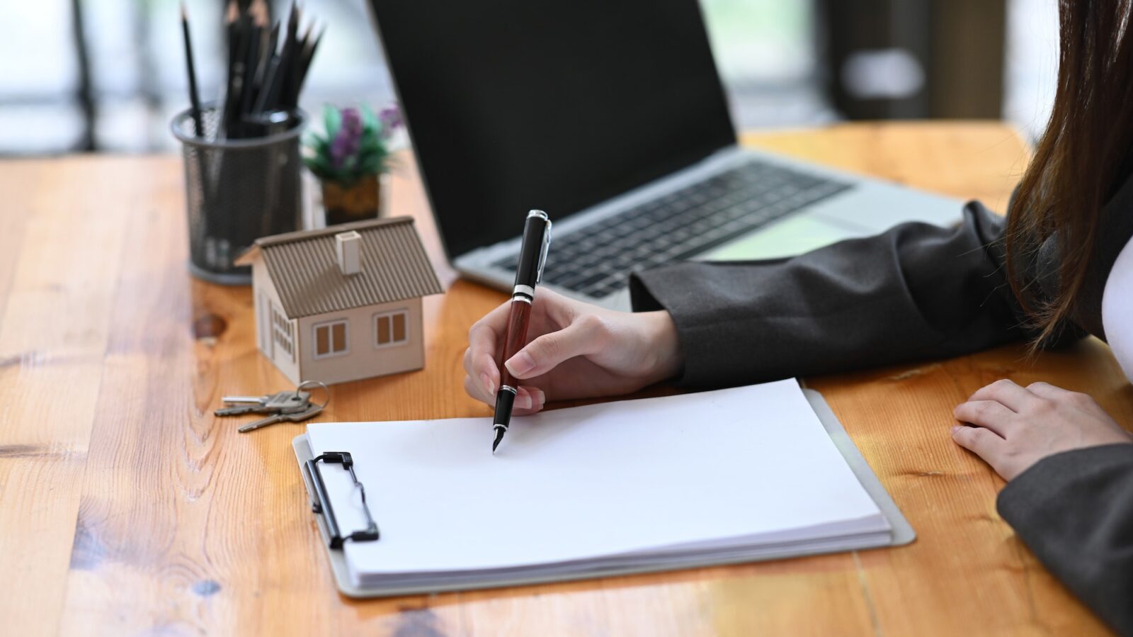 Real estate agent woman analyzing real estate investment data on wooden table.