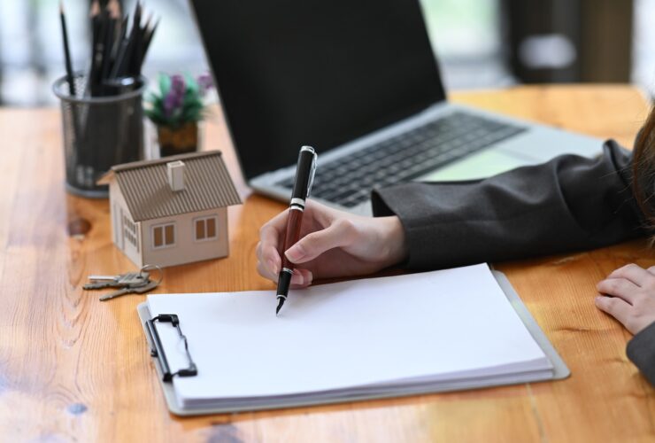 Real estate agent woman analyzing real estate investment data on wooden table.