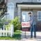 young man with sale board selling his new house