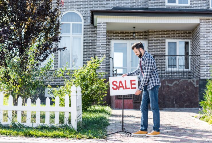 young man with sale board selling his new house