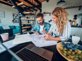 Happy couple using laptop and looking into blueprints of their new home