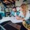 Happy couple using laptop and looking into blueprints of their new home