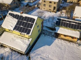 House roof covered with solar panels in winter with snow on top. Energy efficiency and maintenance