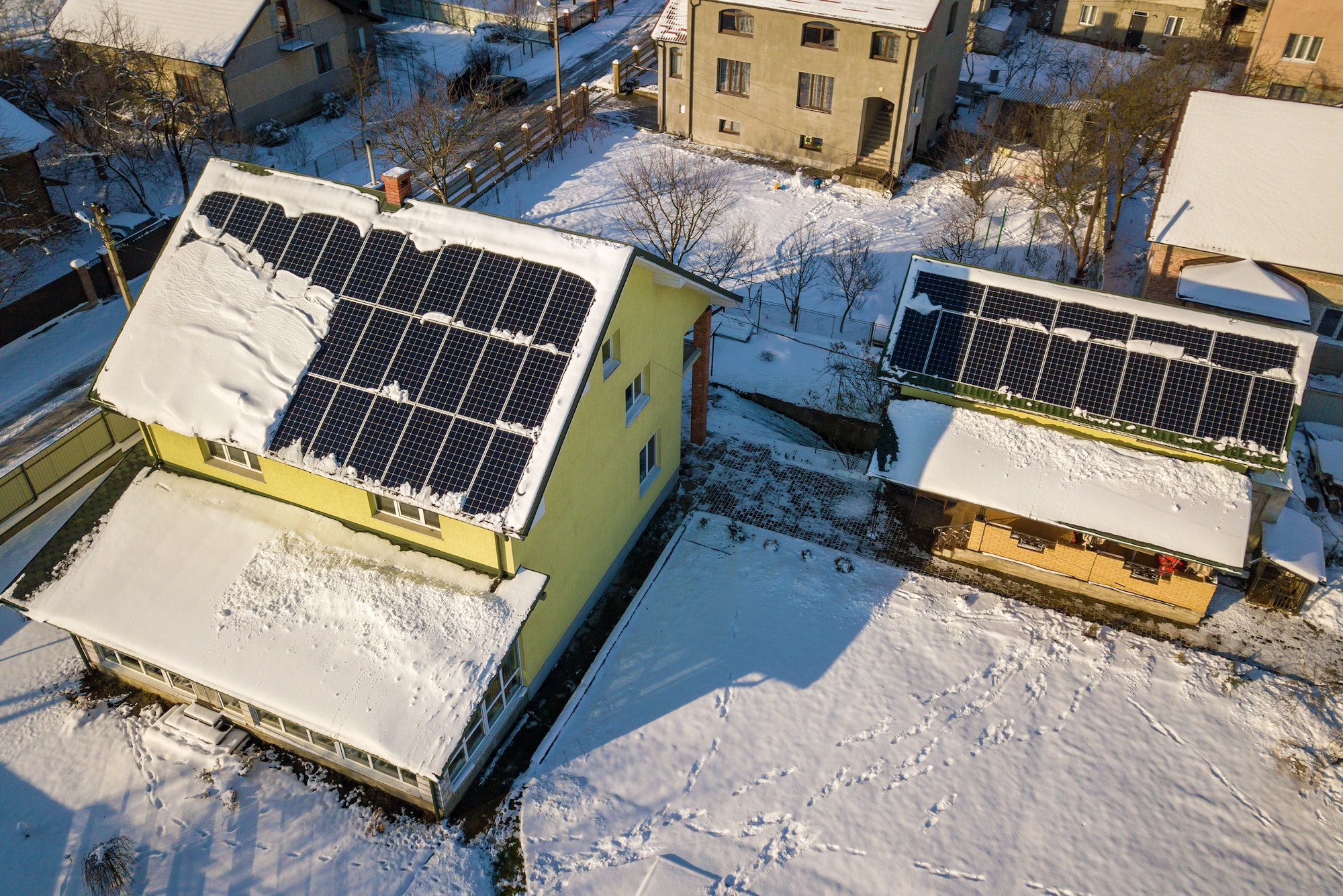 House roof covered with solar panels in winter with snow on top. Energy efficiency and maintenance