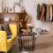Domestic room interior with couches, shelves, small table and rack with clothes