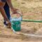 Drawing white lines in a cricket pitch, hands with a brush and white paint, painting straight lines