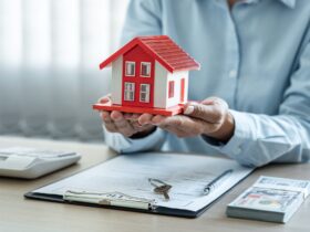 Female real estate agent is use hands holding house of red roof for the concept of real estate