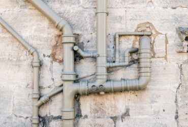 Iron sewer pipes on stone wall background