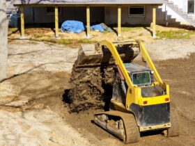 Bulldozer moving, leveling ground at construction site in ground using shovels