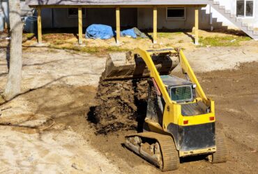 Bulldozer moving, leveling ground at construction site in ground using shovels