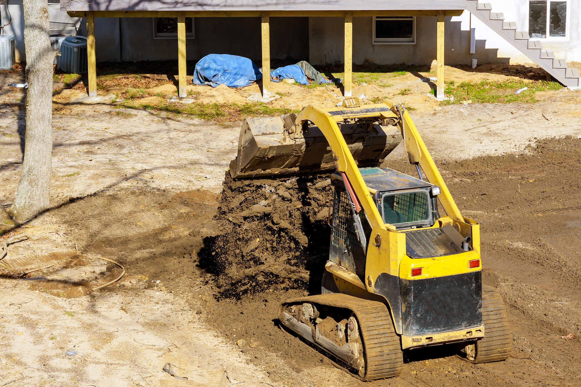 Bulldozer moving, leveling ground at construction site in ground using shovels