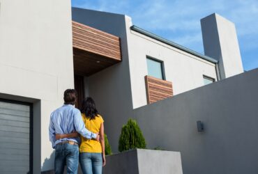 Happy Hispanic couple standing and looking at the new house
