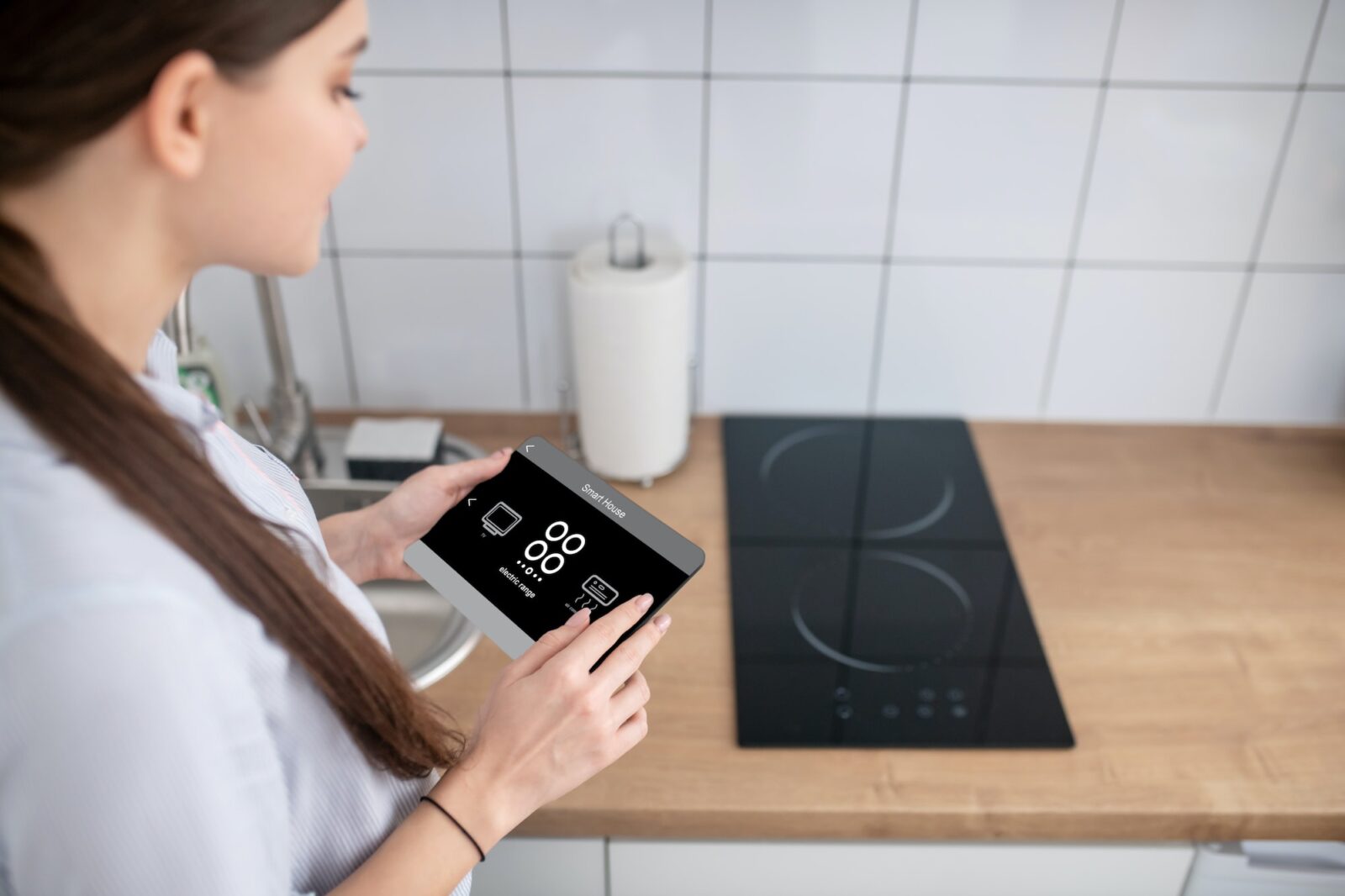 Housewife turning on the cooktop using a gadget