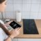 Housewife turning on the cooktop using a gadget