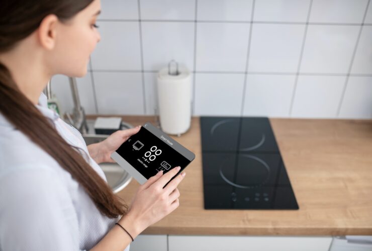 Housewife turning on the cooktop using a gadget