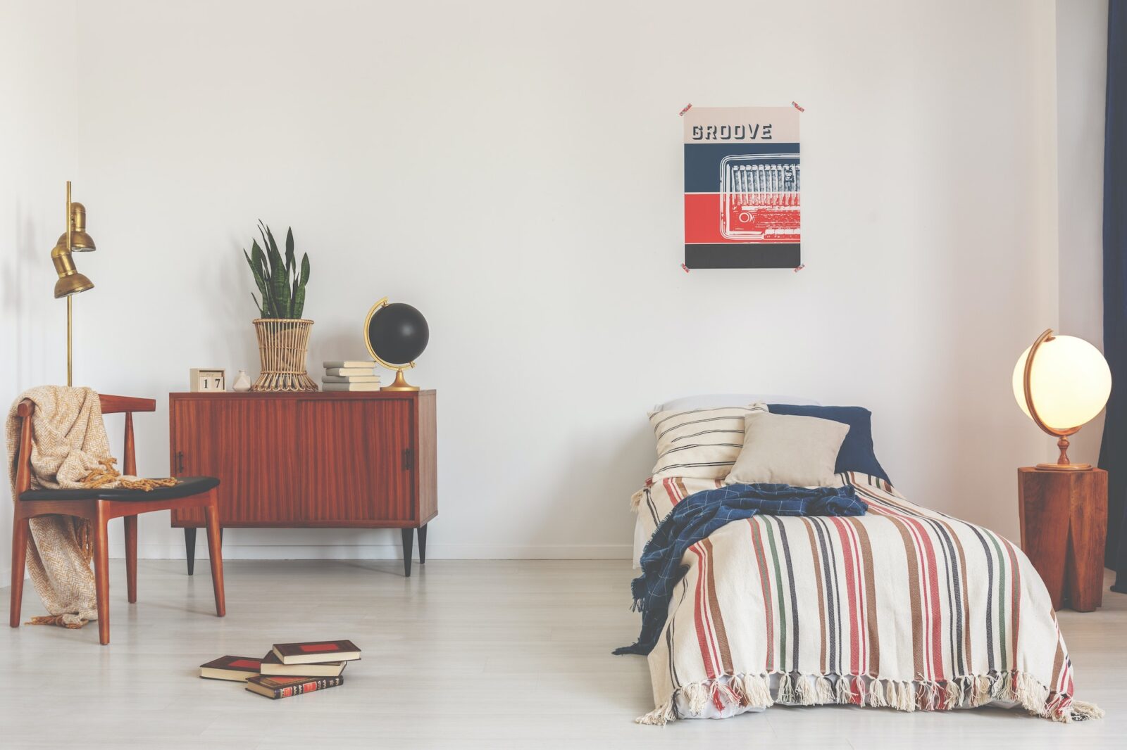 Poster above striped bed in white vintage bedroom interior with