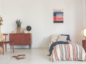 Poster above striped bed in white vintage bedroom interior with