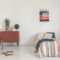 Poster above striped bed in white vintage bedroom interior with