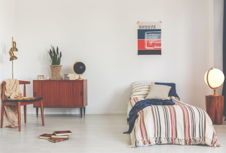 Poster above striped bed in white vintage bedroom interior with