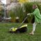 Woman cuts grass with electric lawn mower on backyard