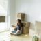 Young woman sitting in new home with glass of red wine while friend is moving fast with cardboard bo