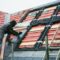 A roofer replacing the tiles on a house roof.