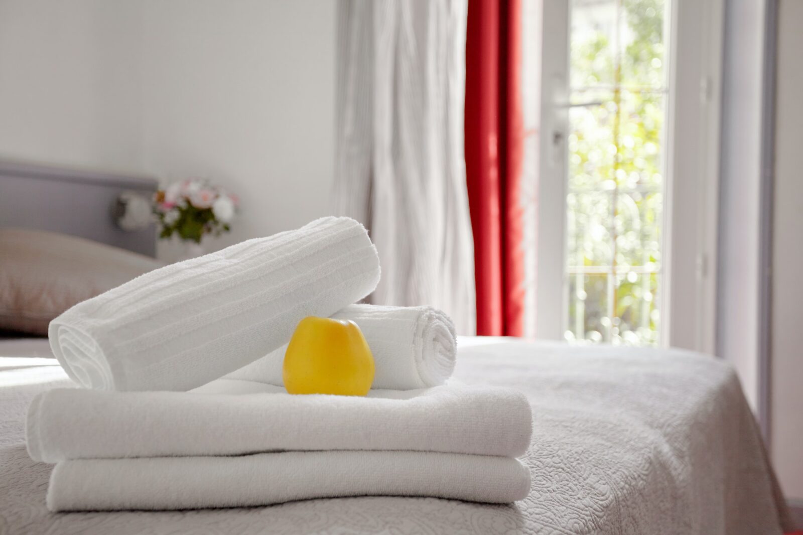 Beautifully and neatly folded white towels lie on the bed in the room against