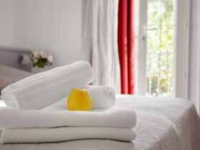 Beautifully and neatly folded white towels lie on the bed in the room against