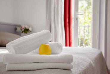 Beautifully and neatly folded white towels lie on the bed in the room against