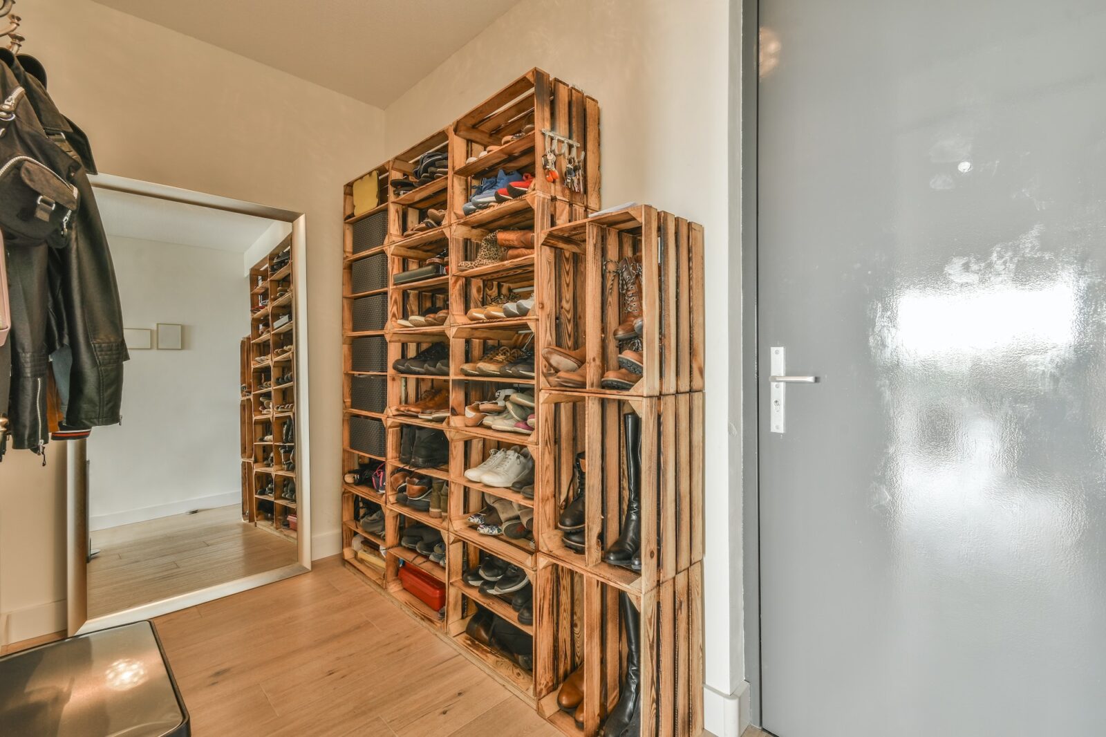 Narrow corridor with shoe rack near doors, white walls and wooden floor