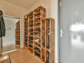 Narrow corridor with shoe rack near doors, white walls and wooden floor