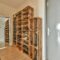 Narrow corridor with shoe rack near doors, white walls and wooden floor