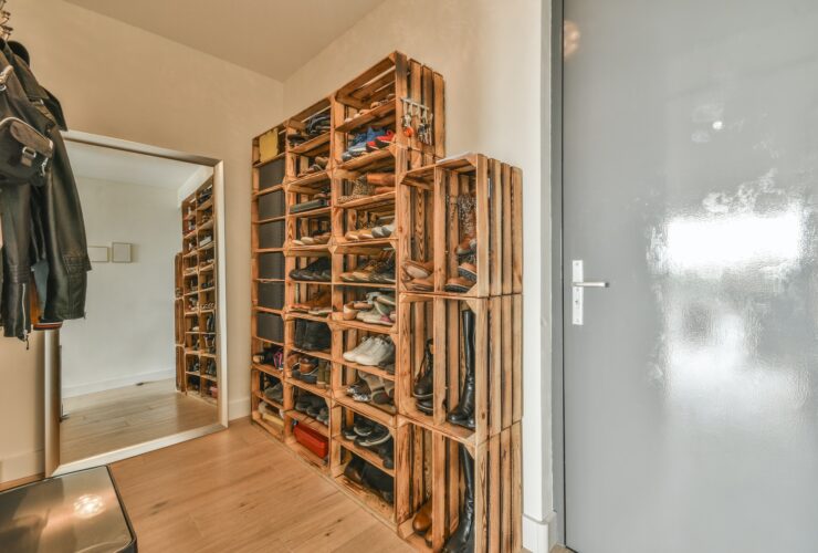 Narrow corridor with shoe rack near doors, white walls and wooden floor