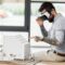 virtual reality architect in virtual reality headset pointing with finger at model of house
