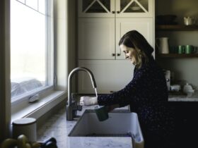 Woman filling up cup at kitchen sink